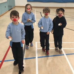 Children playing the egg and spoon race at a Comic Relief event. Rookwood infants school. Hampshire.