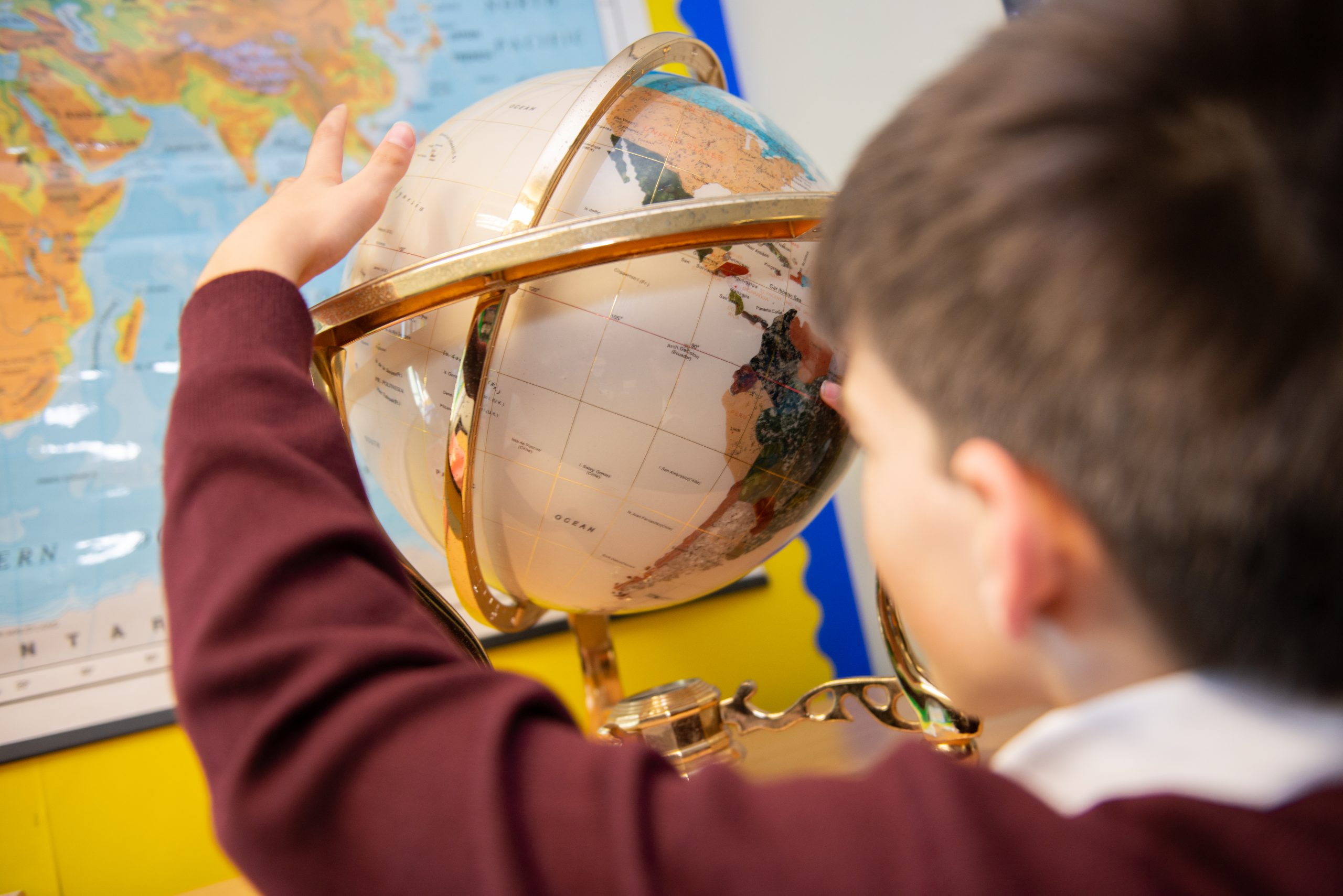 A year 2 Rookwood School student studies a globe in geography class.