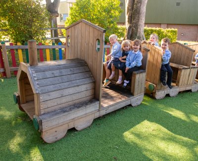 Rookwood nursery children playing on outdoor play equipment shaped like train.