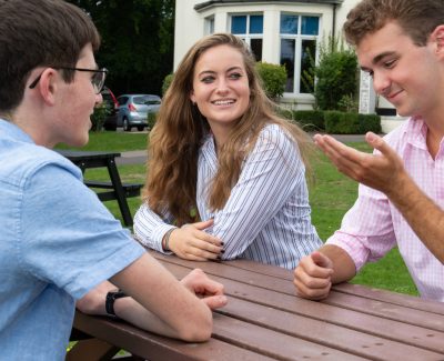 Rookwood School's sixth form students chat on a bench outside in the school's garden in Andover, Hampshire.