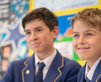 Two young boys dressed in Rookwood School's uniform are smiling whilst being taught in a lesson.