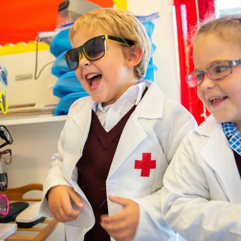 Rookwood School early years students dressed in doctors coats and glasses smiling.